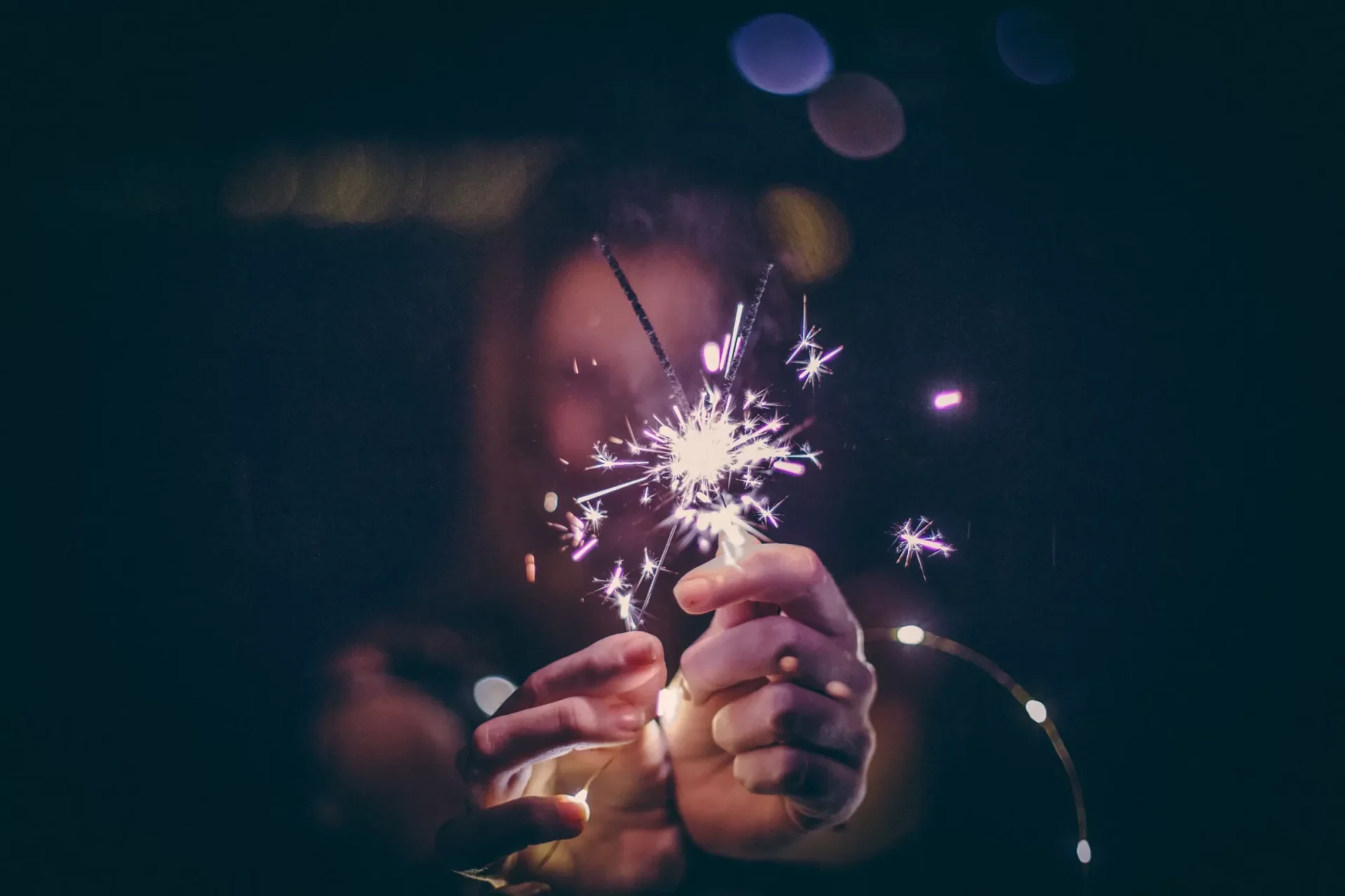 Hands holding a bright sparkler