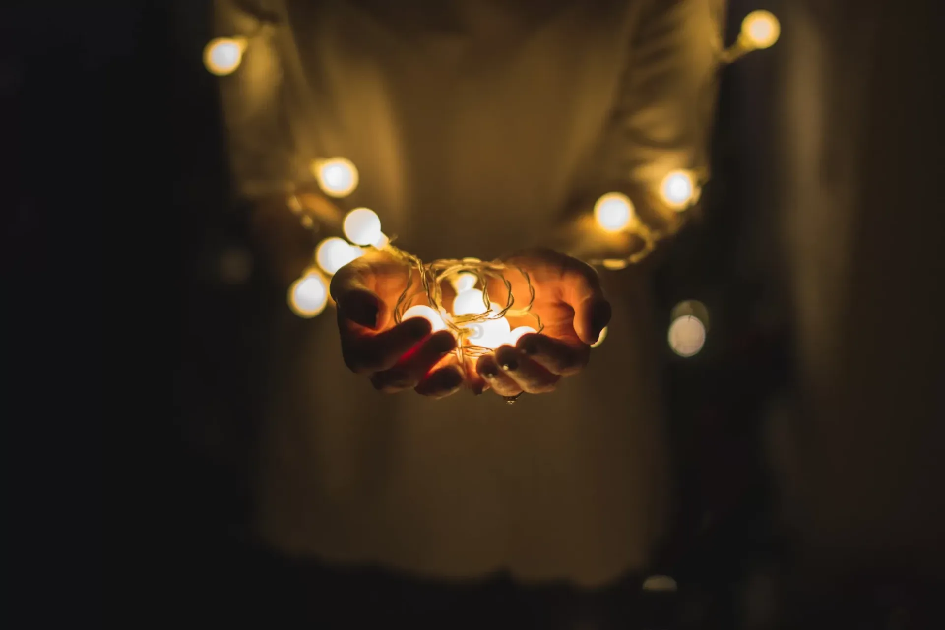Hands cradling glowing fairy lights